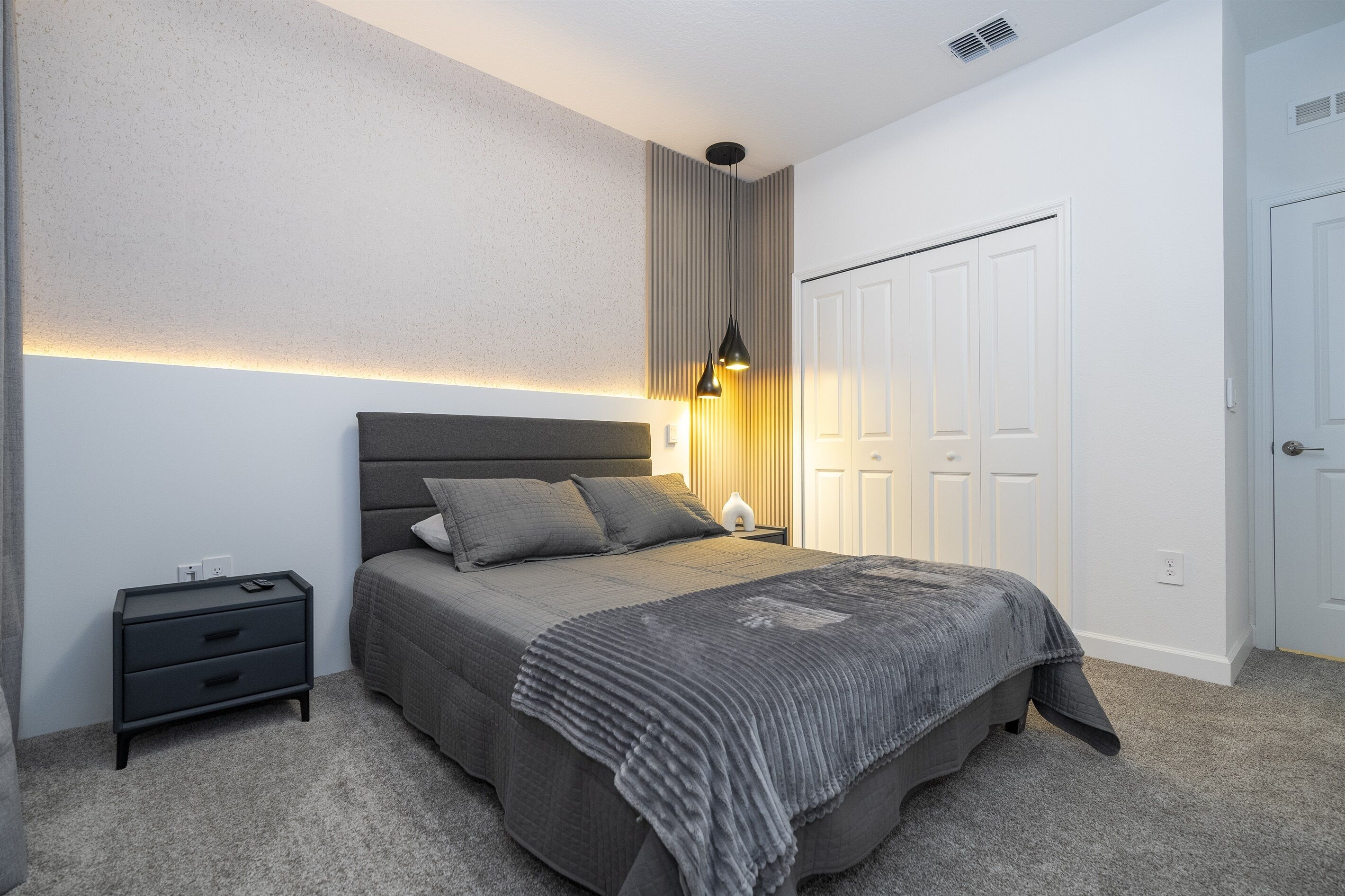 Ein Schlafzimmer mit Bett, Nachttischen, einem Nachttisch und einem Kleiderschrank.