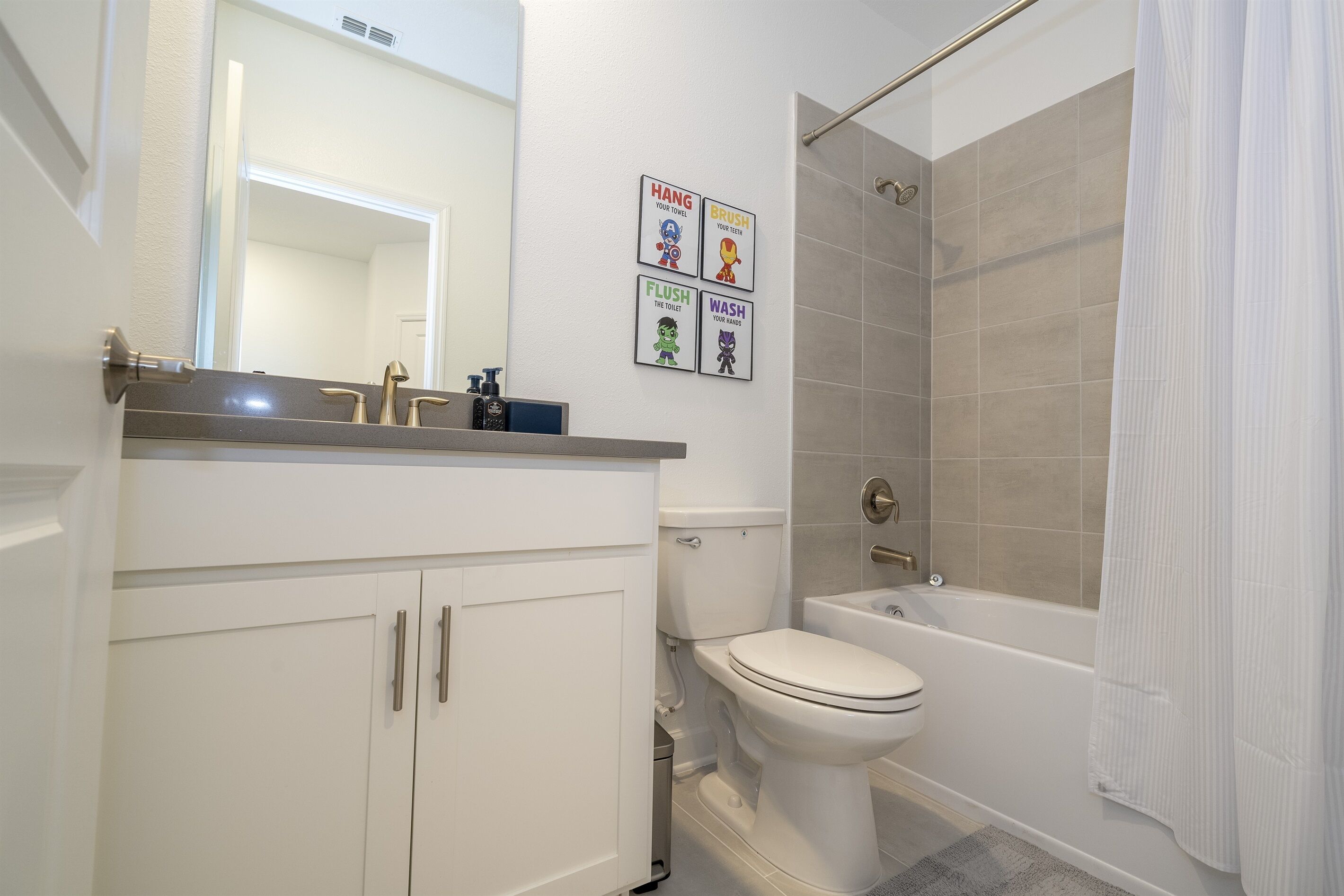 Ein Badezimmer mit Toilette, Waschbecken und Dusche. Vier Schilder an der Wand zeigen Zeichentrickfiguren und Text.