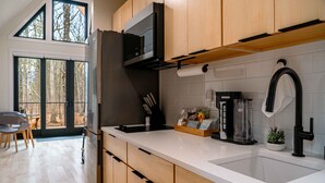 A modern kitchen with wooden cabinets, a stainless steel refrigerator, a microwave, and a coffee maker.