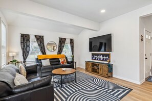 A modern living room with a sofa, coffee table, and a flat-screen TV mounted on the wall.