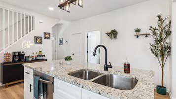 A kitchen with a granite countertop, stainless steel sink, and a black faucet.