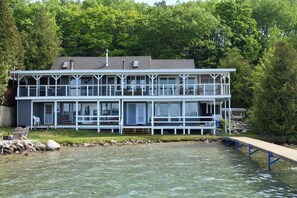 A two-story waterfront house with a dock extending into a lake, surrounded by dense trees. - Ultimate Lakefront Getaway: Hot Tub/Boat Dock/& Game Room! (Beulah)