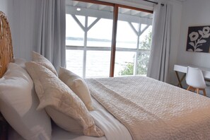 A bedroom with a large bed, white bedding, a desk, and a view of the water. - Ultimate Lakefront Getaway: Hot Tub/Boat Dock/& Game Room! (Beulah)