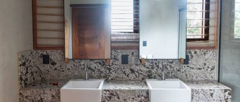 A bathroom with two sinks, wooden beams, and a bench.