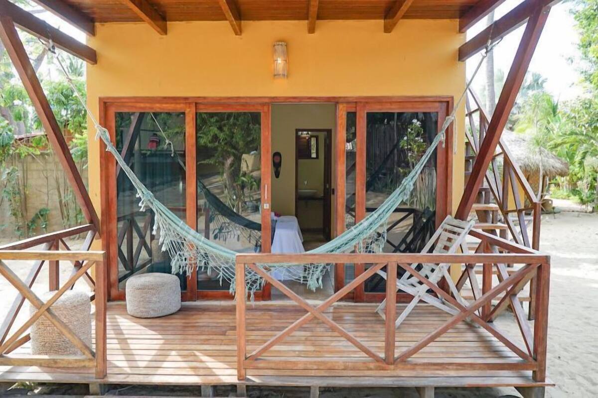 A wooden deck with a hammock, a small round seating area, and a door leading to an interior space.