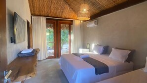 A room with two beds, a wooden ceiling, a TV, and a window with curtains. - Pousada Rota dos Ventos (Cajueiro da Praia)