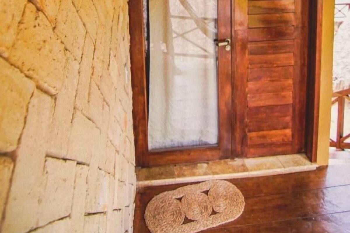 A wooden door with a glass panel, a woven wall hanging, and a stone wall.