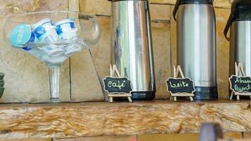 A coffee station with three stainless steel thermos cups labeled 'cafe,' 'leite,' and 'aguarela.'