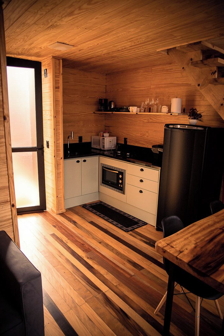 A compact kitchen with wooden cabinetry, a microwave, a refrigerator, and a dining area with a table and chairs.