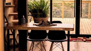 A wooden dining table with two chairs, a potted plant, and a bottle on the table. - Rancho Denver (Urubici)