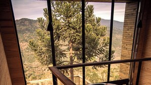A wooden staircase leading to a room with a bathtub, large windows offering a view of trees and hills. - Rancho Denver (Urubici)