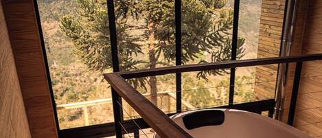 A wooden staircase leading to a room with a large window overlooking a mountainous landscape.