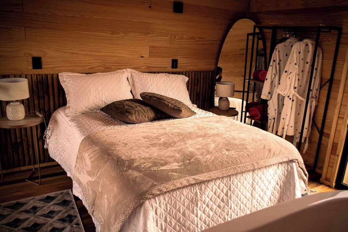 A cozy bedroom with a wooden headboard, a quilted bedspread, and a bedside table with a lamp.