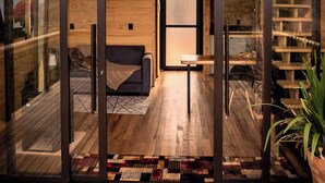 A modern interior with a wooden floor, a sofa, a table, and a staircase leading to an outdoor area. - Rancho Denver (Urubici)