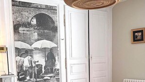 Een eethoek met een ronde tafel, witte stoelen en een geweven hanglamp.