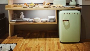 Een compact keuken met houten planken, een magnetron, een minibar en diverse keukenaccessoires.