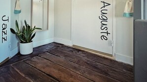 Une pièce avec un plancher en bois, une plante en pot et deux portes portant les inscriptions « Jazz » et « Augustine ».