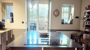 Une cuisine moderne dotée d’un îlot central, de luminaires suspendus et offrant une vue sur l’extérieur.