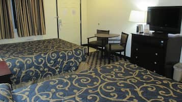 Habitación de hotel con dos camas, un escritorio con silla, televisión y lámpara.