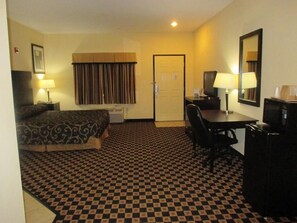 A hotel room with a checkered floor, a bed, a desk with a chair, a television, and a mirror. - Scottish Inns Killeen Harker Heights  (Killeen)