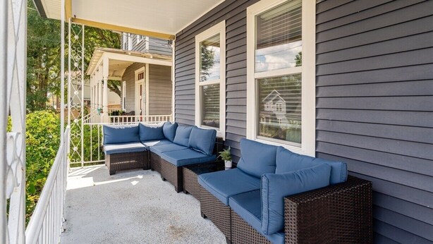 A covered porch with wicker furniture and a railing.