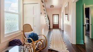 A hallway with a wooden chair, a table, and a rug.