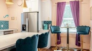 A modern kitchen with a central island, bar stools, and pendant lighting.