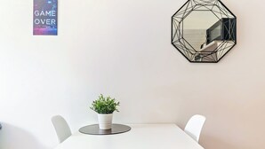 A white table with a potted plant, a geometric mirror, and a poster on the wall. - Cosy air-conditioned studio with secure parking (Lyon)