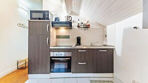A compact kitchen with a built-in oven, microwave, and coffee maker. - Cosy air-conditioned studio with secure parking (Lyon)