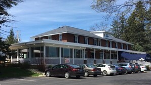 A two-story building with a covered front porch and a parking lot with several cars. - Sunshine Room for 2 #7 (Central Lake)