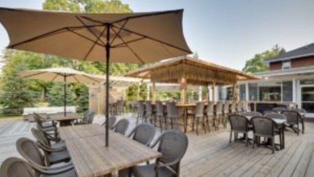 An outdoor patio with wooden tables and chairs, covered by large umbrellas. - Sunshine Room for 2 #7 (Central Lake)