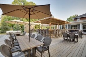 An outdoor patio with wooden tables and chairs, covered by large umbrellas. - Sunshine Room for 2 #7 (Central Lake)