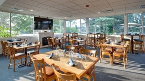 A spacious indoor dining area with multiple tables and chairs, large windows, and a fireplace. - Sunshine Room for 2 #7 (Central Lake)