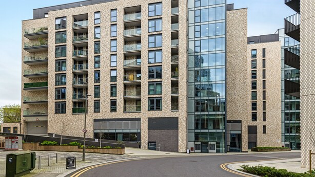 Un immeuble résidentiel à plusieurs étages, doté d’une architecture moderne, de balcons et de grandes fenêtres.