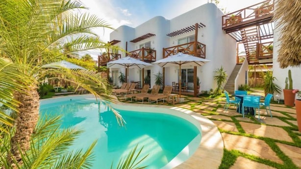 A modern resort with a swimming pool, outdoor seating, and a thatched-roof structure. - La Plage Hotel Boutique (Cajueiro da Praia)