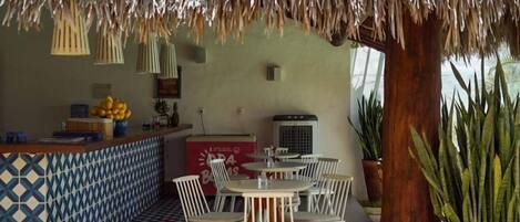 A restaurant with a thatched roof, outdoor seating, and a tiled floor.