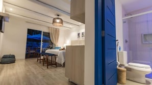 A modern hotel room with a dining area, a large bed, and a bathroom with a shower and toilet. - La Plage Hotel Boutique (Cajueiro da Praia)