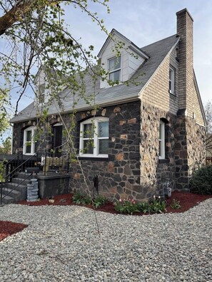 A stone house with a chimney, a front porch, and a gravel driveway. - Historic Baldwin Home in Klamath Falls (Klamath Falls)