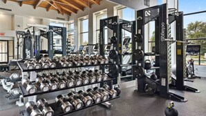 A gym with weightlifting equipment, including dumbbells and a squat rack.