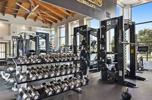 Une salle de sport équipée de matériel de musculation, notamment des haltères et un support à squats.