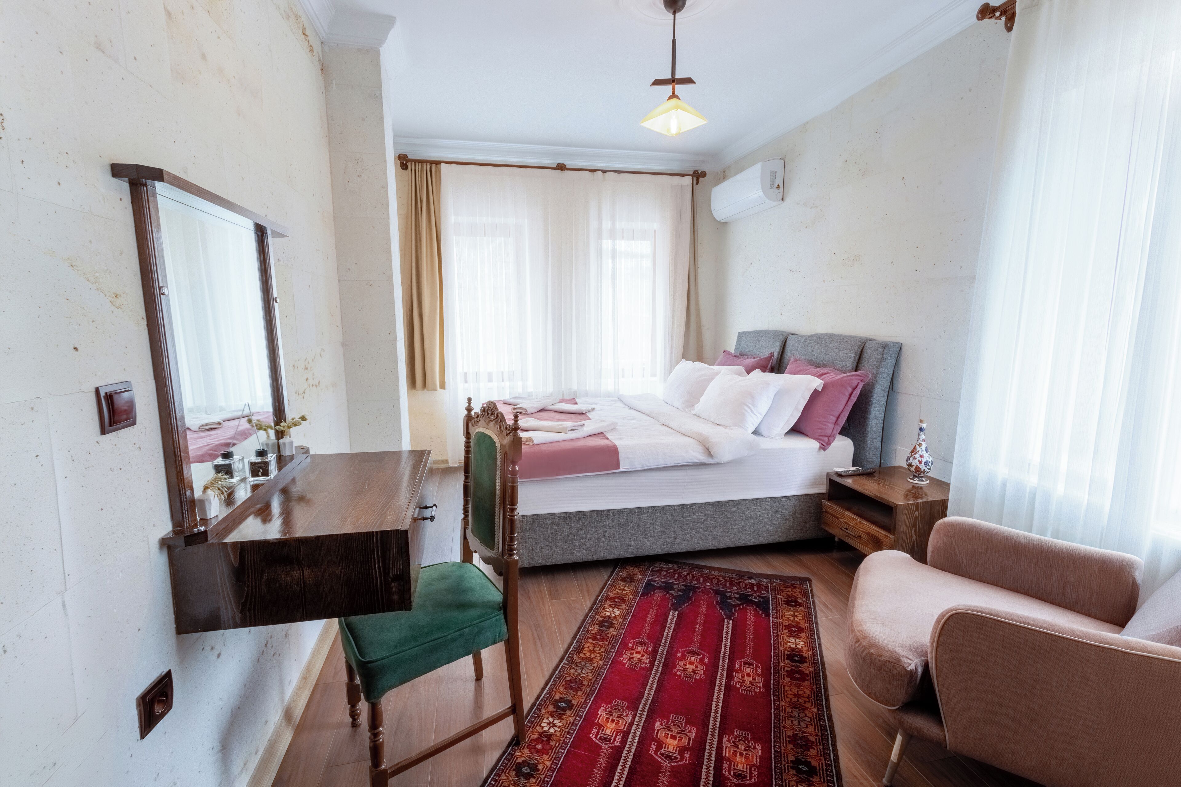 Ein Schlafzimmer mit einem Bett, einem Schreibtisch, einem Sessel, einer Couch und einem Teppich.