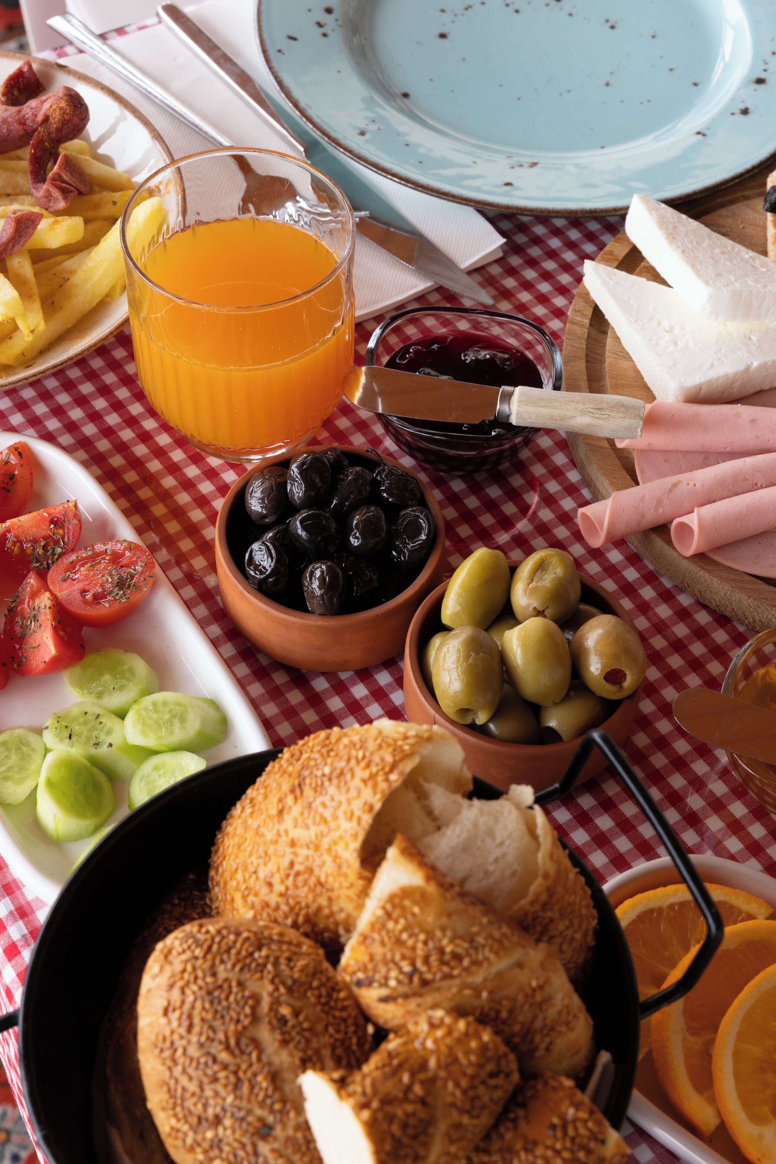 Une table avec des aliments, un verre de jus d’orange et un bol d’olives.