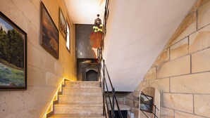A staircase with stone steps and a metal railing, leading to a landing with a view of a landscape painting. - Yellow Stone Suites (Nevsehir)