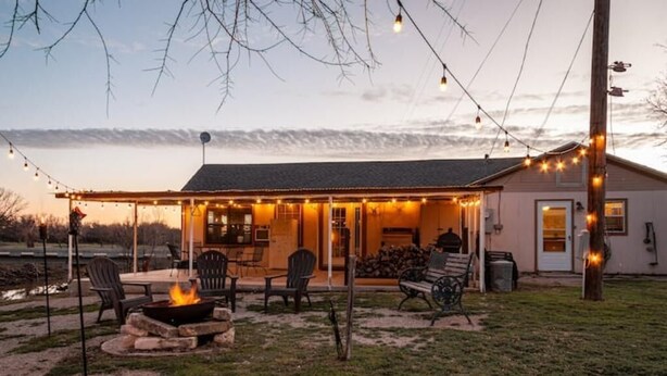 Una casa con un porche techado, mobiliario exterior y una chimenea.