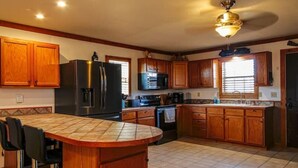 Una cocina con armarios de madera, un refrigerador negro, un microondas, una estufa y un salpicadero de azulejos.
