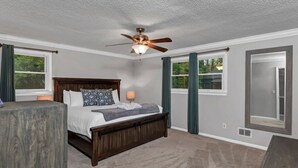 A bedroom with a bed, a ceiling fan, a window, and a mirror. - The Quail's Nest of Harbison | Sleeps 8 (Columbia)