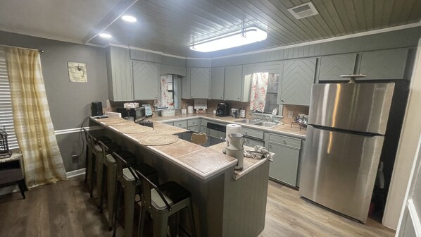 Una cocina moderna con una isla central, taburetes de bar, un refrigerador y un microondas.