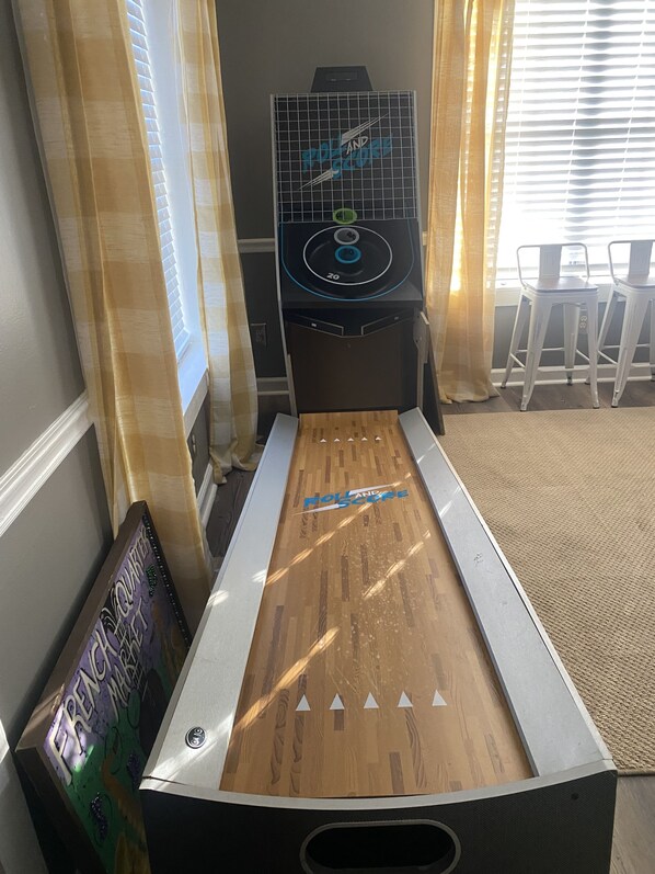 Una máquina de pinball con tablero de madera y parte superior negra con rejilla.