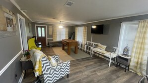 A living room with a sofa, a coffee table, a foosball table, and a TV.