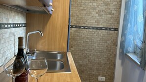 A kitchen with a wooden countertop, a sink, and a bottle of wine. - Casa Kris in the center of Otranto (Otranto)